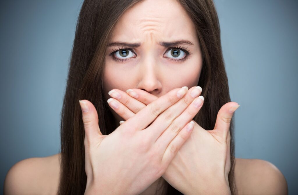 A young woman covering her mouth because she's worried about her bad breath.