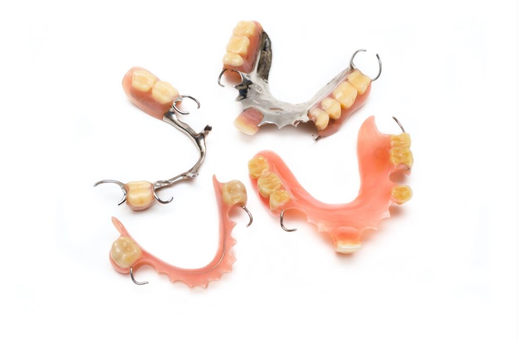 A close-up of 4 different types of dentures on a white background.