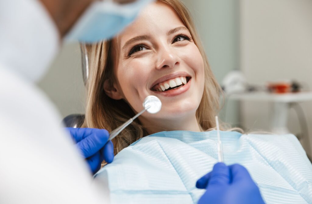 A patient smiling at her dentist after a professional cleaning as the dentist prepares to apply fluoride treatment.