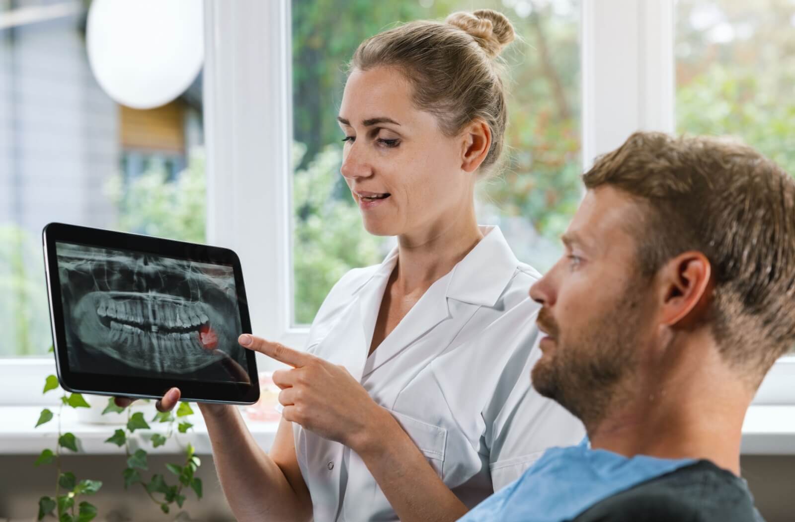 A dentist reviews a patient's x-rays with them during a consultation for future dental implants.