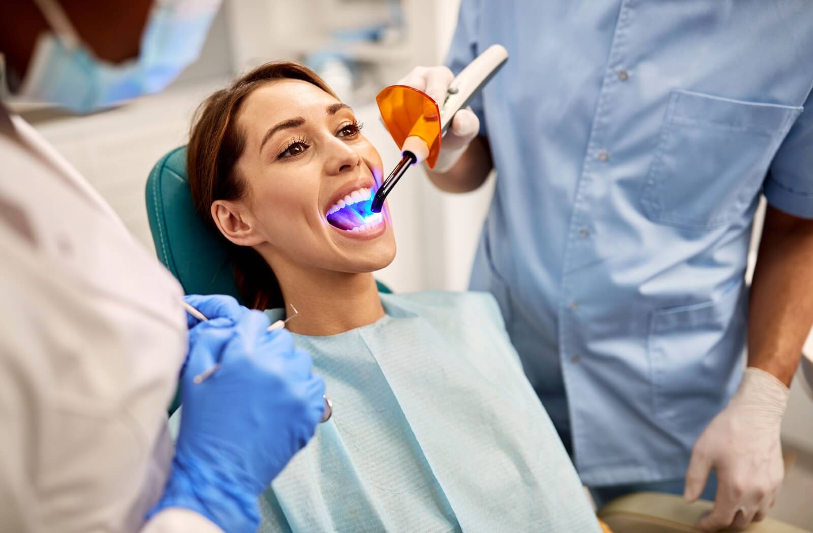 A dentist cures a patient's cavity filling during their appointment.